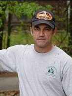 A man wearing a light colored T-shirt and a dark baseball hat