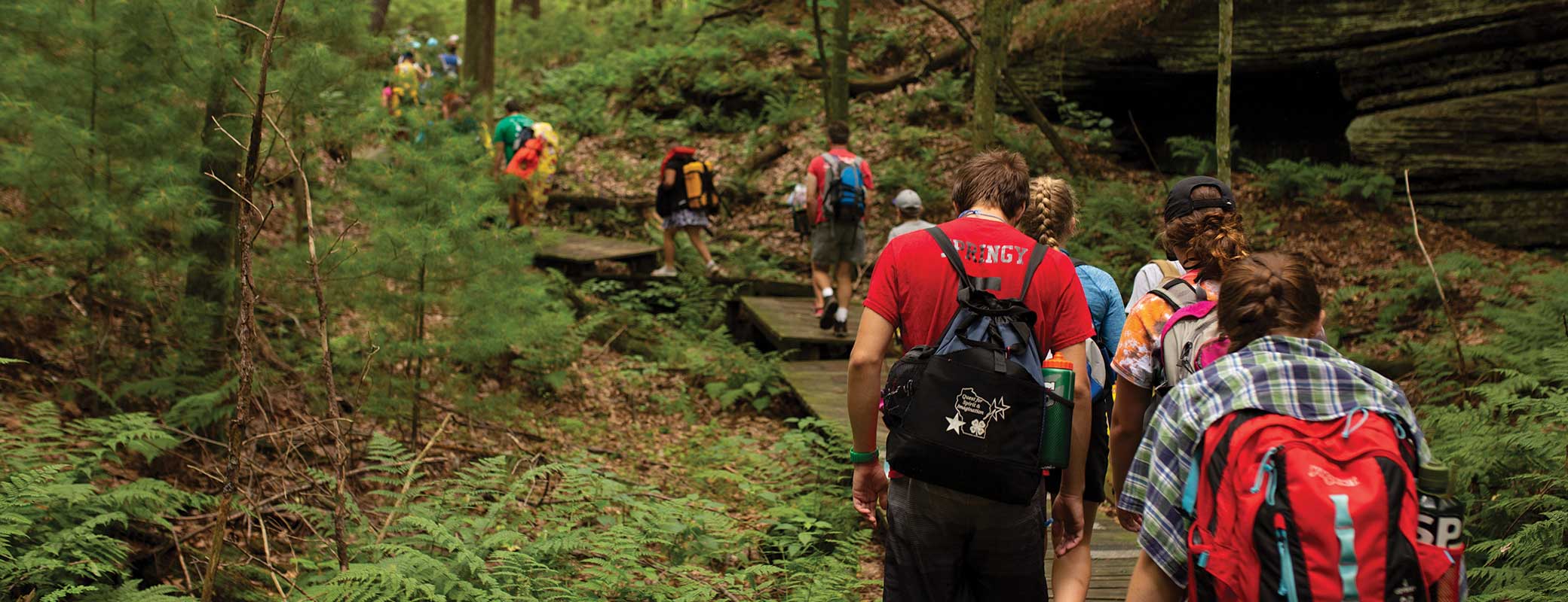 A group of students hiking in a wooded rocky area