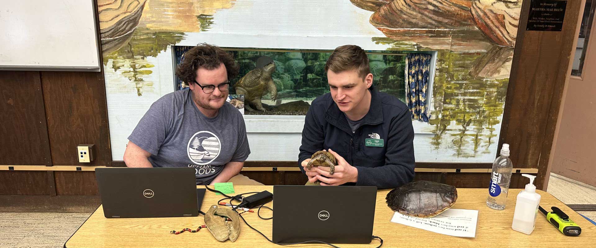 two men on a virtual meeting talking about a turtle that one is holding