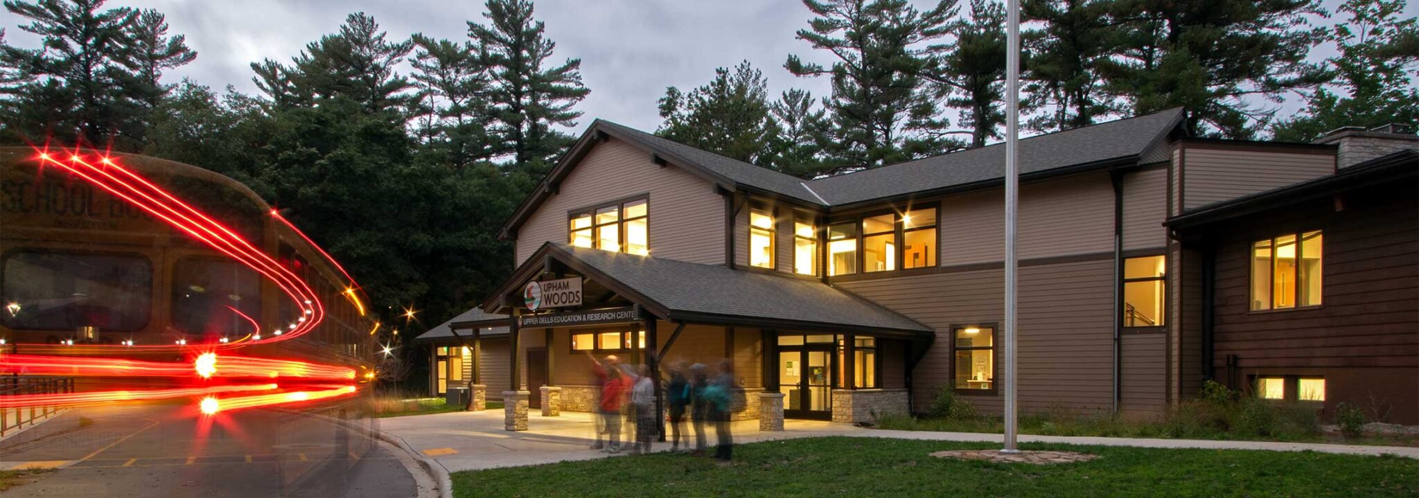 Upham woods front entrance in the early evening with a small group of people standing on the sidewalk in front of the building