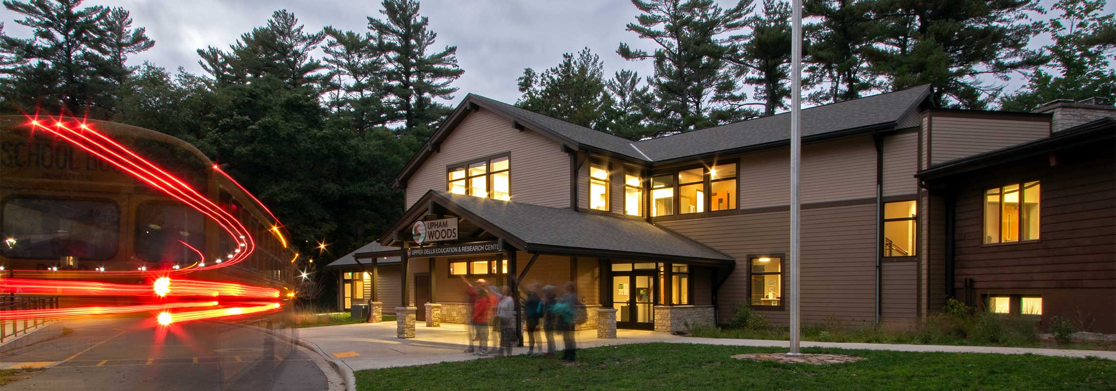 Upham woods front entrance in the early evening with a small group of people standing on the sidewalk in front of the building