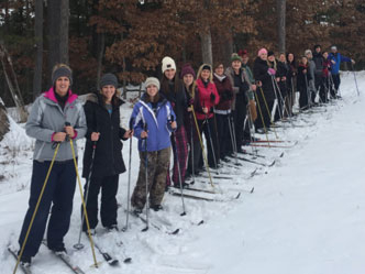 A group of cross country skiers in a long line