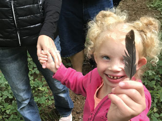 A little girl holding a black feather