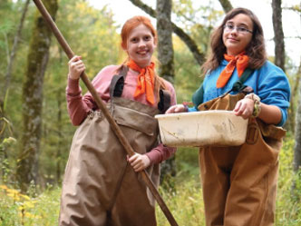 Two girls wearing waders working in a stream