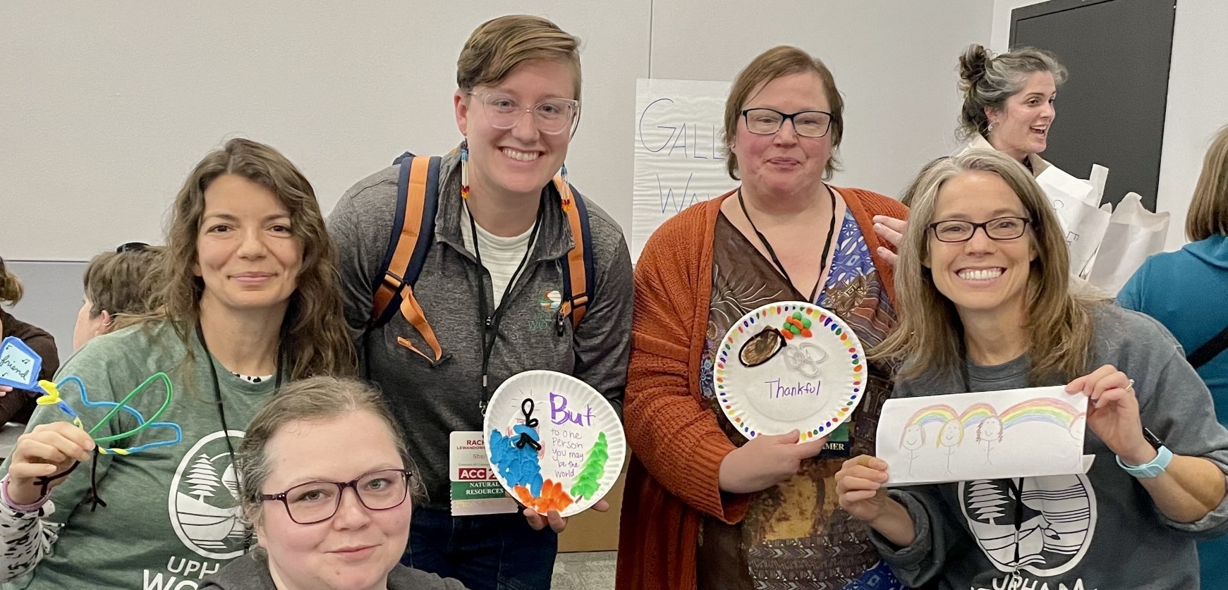 Upham Woods staff standing with art projects and smiling 